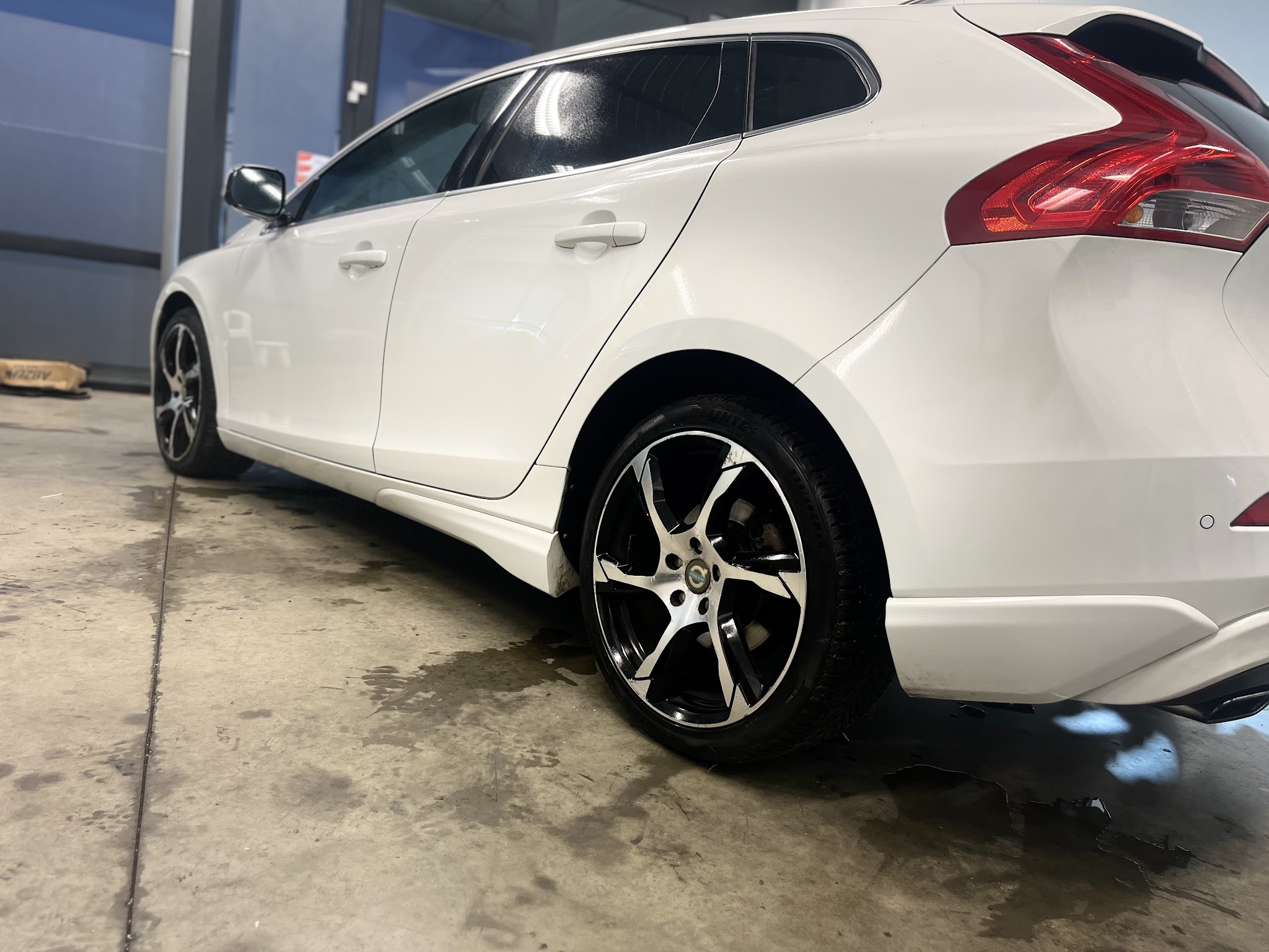 Witte Volvo V60 in de werkplaats, gezien vanaf de achterzijde met lichtmetalen velg
